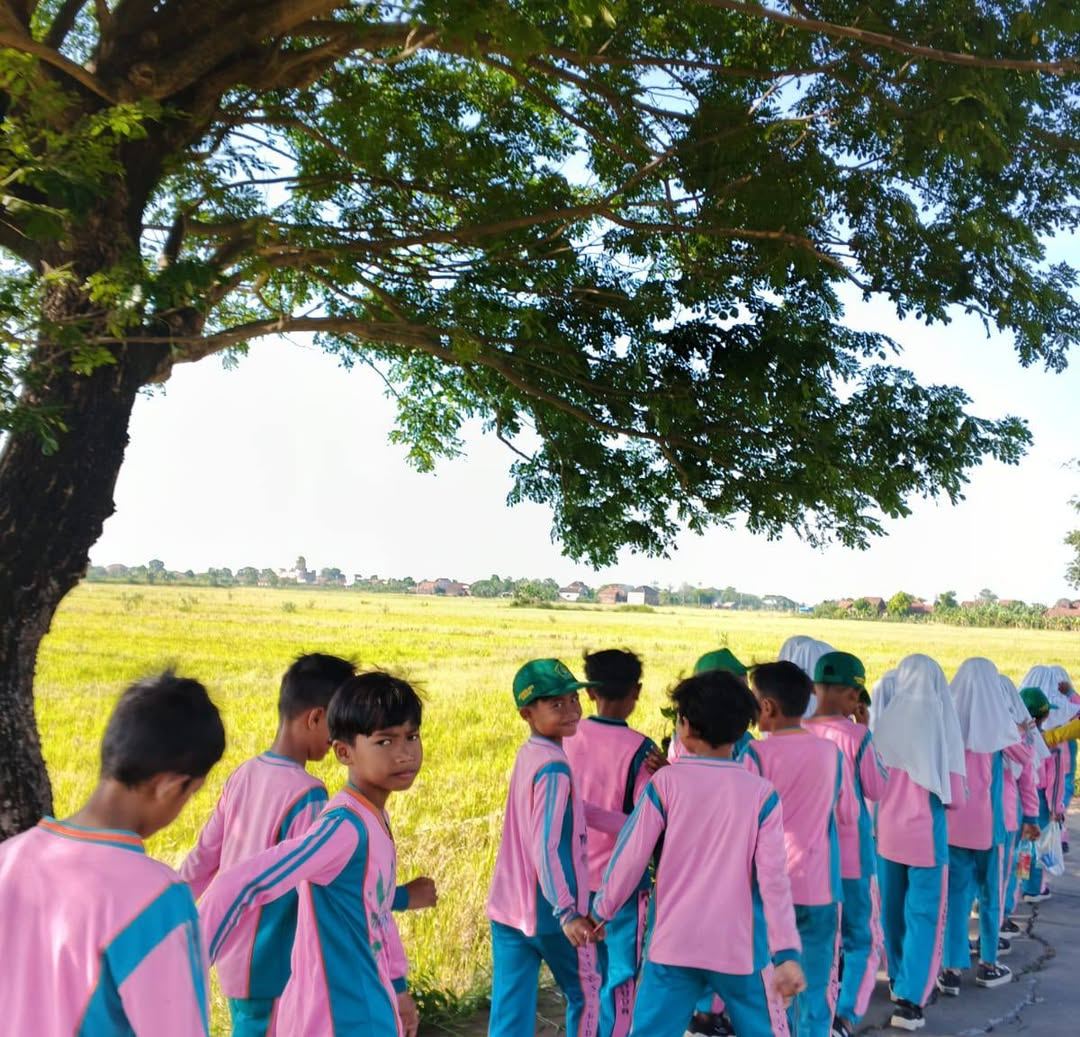 Siswa MI Syumusul Huda berjalan melintasi sawah di Desa Kuanyar
